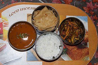 Un tiffin ouvert : quatre mets du repas gujaratis : (dans le sens des aiguilles d'une montre à partir de la gauche) daal (soupe de lentilles), rotli (pain plat), shaak (légumes cuits), bhat (riz)