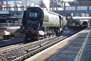 A green steam locomotive passing through Reading station