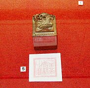 Seal, decorated with a dragon, and its imprint against a red background