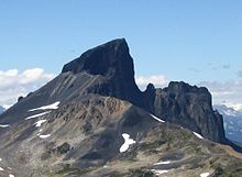 Скалистая гора, главная вершина которой окружена хребтом справа, а левый фланг покрыт щебнем.