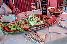 Photo of restaurant table holding a platter featuring unshelled lobster legs and claws