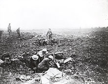 Photo en noir et blanc de militaires dans des cratères d'obus avec des mitrailleuses et des munitions