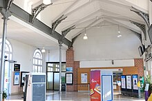 Intérieur du bâtiment de la gare, très lumineux grâce aux murs et plafonds de couleur blanche.