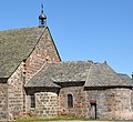 Photo en couleur sur fond de ciel bleu d'une partie de bâtiment en pierre avec toits pentus sombres