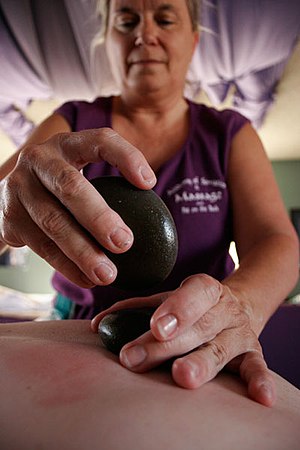 De Etta Sanchez performs a hot stone massage a...