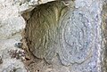 Une pierre où sont sculptés deux médaillons, sont représentés : sur celui de gauche, l'Agneau de Dieu et sur celui de droite : un coq rappelant le reniement de Pierre