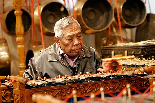 Man playing a gamelan, a traditional Indonesian instrument
