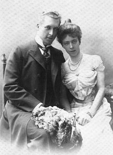 Albert et Élisabeth posent assis une gerbe de fleurs sur les genoux