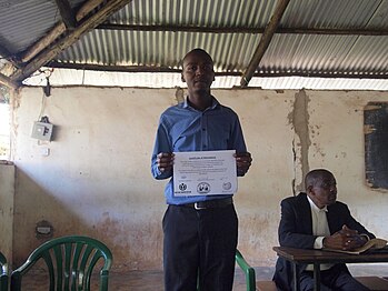 A participant holding his conference attendance certificate (they received more pretty ones later after we found a designer)