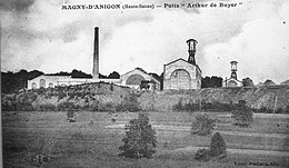 Photo noir et blanc un ensemble de bâtiments industriels typés 1900 avec deux grand chevalements (tour avec bigue) métalliques et cheminée d'usine.