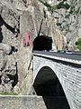 Ponte stradale con il tunnel e il diavolo della leggenda dipinto sulla roccia.