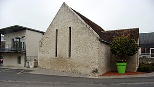 Photographie en couleurs d'un bâtiment sans étage, avec un haut pignon et deux baies étroites et hautes.