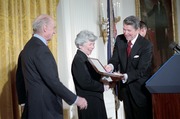 President Ronald Reagan presents Roberta Wohlstetter with the Presidential Medal of Freedom. Also pictured: Albert Wohlstetter and Paul Nitze (obstructed by Mr. Wohlstetter). The East Room of the White House, Washington, D.C., 7 November 1985. Photograph by Peter J. Souza, courtesy of the Ronald Reagan Presidential Library.