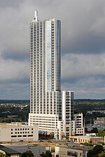 View of the 360 Condominiums from the north; the building has a blue glass facade; there is a setback 1/3 of the way up and a spire on the top of the tower.