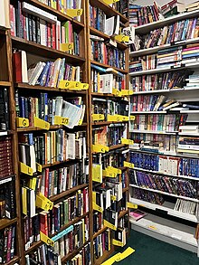 bookshelves with approximately 200 books against a wall with shelf labels