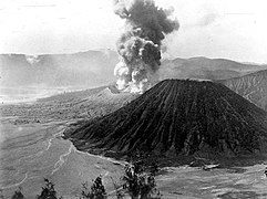 Gunung Batok dengan latar belakang Gunung Bromo yang sedang aktif di awal abad ke-20. Foto koleksi KITLV.