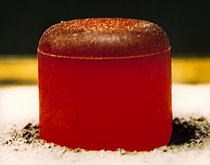 A pellet of PuO2 as used in the RTG for the Cassini and Galileo missions. This photo was taken after insulating the pellet under a graphite blanket for several minutes and then removing the blanket. The pellet is glowing red hot because of the heat generated by radioactive decay (primarily a). The initial output is 62 watts. Radioisotope thermoelectric generator plutonium pellet.jpg