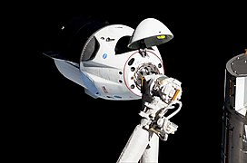 Crew Dragon im Anflug an die ISS; im Vordergrund der (nicht verwendete) Canadarm2