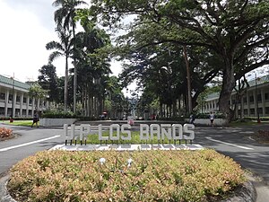 A sign in the foreground reads "P. P. Los Baños; several buildings are seen in the background