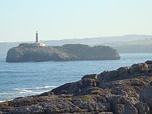 Panoramo de la insulo kun lumturo, vide de plaĝo en Santandero.