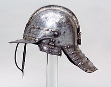 An English lobster-tailed pot helmet c. 1630-1640, with neck protection (the "lobster tail"), three-barred face protection, a peak and a longitudinal comb on the skull; the hinged cheekpieces are missing Helmet for a Harquebusier MET sfsb2012.15 002.jpeg