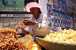 Femme vendant des chips et des amuse-gueule frits dans des paniers au bord de la rue