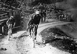 Black and white image of cyclists on a sandy road.