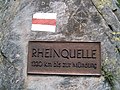 Plakett ved Tomasee som markerer Rhinens kilde. Elvas lengde til munningen er i virkeligheten 1 230 km. Tallet her kan skyldes at to tall ble byttet om.[3]