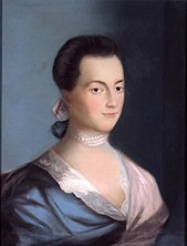 Woman with deep black hair and dark eyes wearing a blue and pink dress