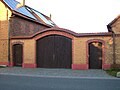 Hofmauer eines Bauernhofes mit großem Torbogen und zwei kleinen Pforten