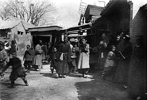 Groupe de Chinois des deux sexes, les femmes qui y figurent sont des Tartares, reconnaissables à l’absence de déformation des pieds et à la coiffure