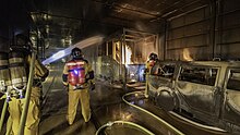 Feuerwehrangehörigen im Strassen-Übungstunnel der International Fire Academy üben einen Löschangriff auf brennende Fahrzeugattrappen
