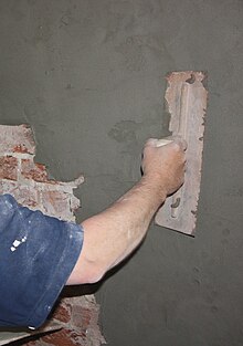 Lavoratore impegnato ad applicare l'intonaco su una parete