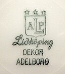 Undersidan av en assiett från (ALP) AB Lidköpings Porslinsfabrik med dekor av Louise Adelborg.