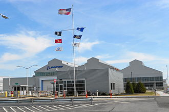 Boeing plant in Ridley Park, Pennsylvania – a building with aluminum siding, parking lot in front, and a flagpole with seven flags