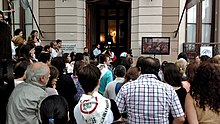 Multitud frente a la puerta del edificio observando en una pequeña pantalla lo que se desarrolla al interior del Juzgado Federal de Paraná