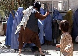 A member of the Taliban's religious police beating an Afghan woman in Kabul on 26 August 2001 Taliban beating woman in public RAWA.jpg