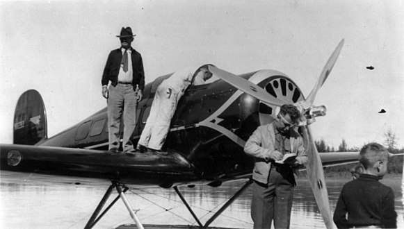 Will Rogers auf der Tragfläche und Wiley Post im Vordergrund mit Augenklappe, Fairbanks (Aug. 1935)