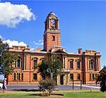 Double storey red brick building with centrally placed tower and decorative sandstone detail, including sandstone portico on front façade. Timber doors and windows. Market hall at rear of building with corrugated iron roof and verandah. The building was erected by the builders Kelly and Anderson of Johannesburg. The cornerstone was laid on 2 August 1907 by Sir Hamilton Goold-Adams, Lieutenant-Governor of the Orange River Colony. The building was officially inaugurated on 7 September 1908. Architectural style: Neo-classical. Type of site: Town Hall Current use: Town Hall. This red brick building with its sandstone ornamentation was designed by Price and Agutter and erected in 1907-1908. It is one of the most impressive town halls in the Free State and a landmark in Harrismith.
