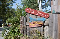 "A series of signs nailed to a wooden fence. They include the following: a red sign that reads Main Street, a blue arrow pointing right, and a pink sign that says Mayor Stubbs with an arrow pointing in the same direction. Mayor Stubbs is a cat that people like to say runs the town."