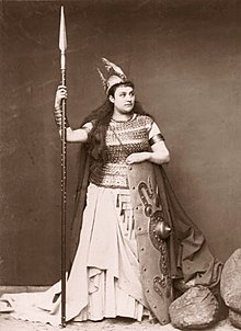 Black-and-white photograph of a woman dressed in her opera costume, with armor, shield, spear and helmet