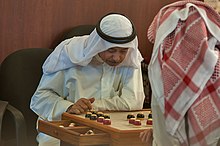Two Qataris playing the traditional board game of damah Board game damah at Souq Waqif.jpg