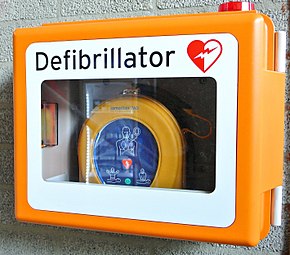 An automated external defibrillator stored in a visible orange mural support Defibrillator-809447 1920.jpg