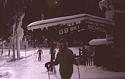 A skier standing in front of a sign that reads "GB Ski School".
