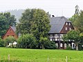 Dreiseithof mit Wohnhaus (Umgebinde), paralleler Scheune, vorn massiv, hinten Holz, Torpfeilern und Resten der Hofmauer