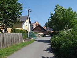 Ulička v Zářečí, v pozadí ruiny továrních budov