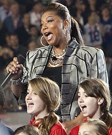 Latifah performing God Bless America at Super Bowl XLIV in 2010 Super Bowl 44 Queen Latifah God Bless America (4344821074) (cropped).jpg