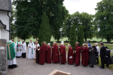 The procession waiting to go inside for the Sunday mass and funeral of Sister Marianne, the first nun in the Church of Sweden since the reformation. At the end are nuns from Alsike Monastery. Alsike Kyrka 2023 funeral of sister Marianne Nordlund.png