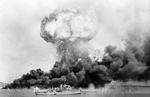 Öljyvaraston räjähdys ilmaiskun aikana Darwinissa 19. helmikuuta 1942. Taustalla HMAS Deloraine, joka pakeni vahingoittumatta.