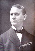 Portrait d'un homme en noir et blanc. Il porte une veste et un nœud papillon.